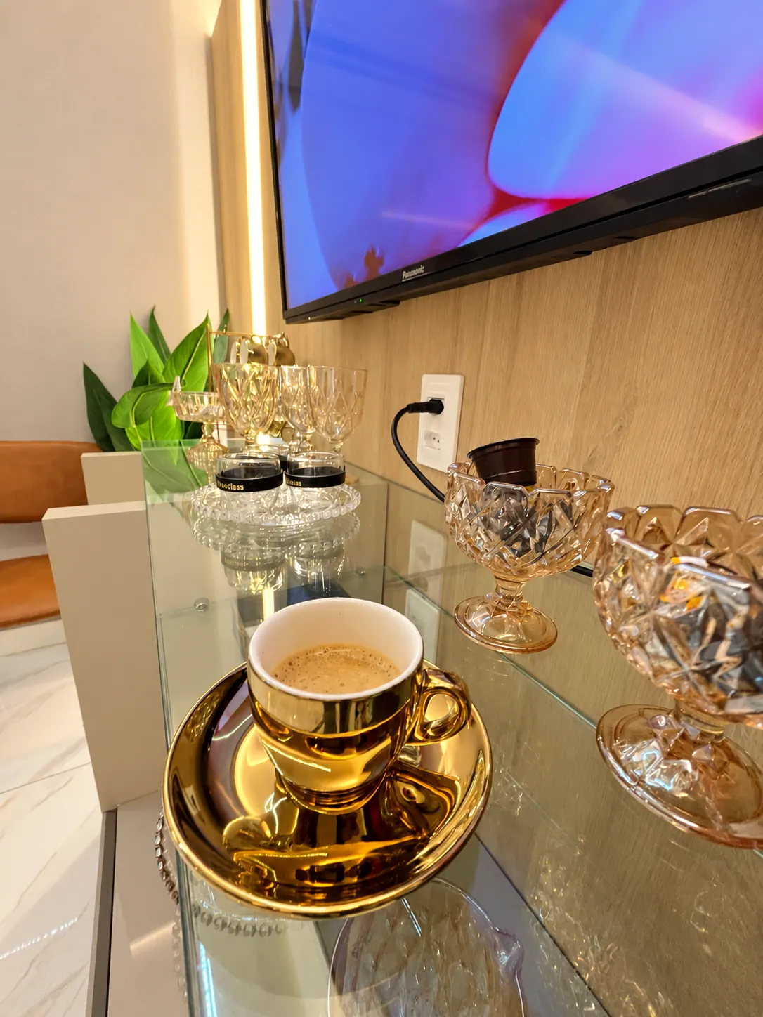 Café servido em xícara dourada ao lado de taças de cristal