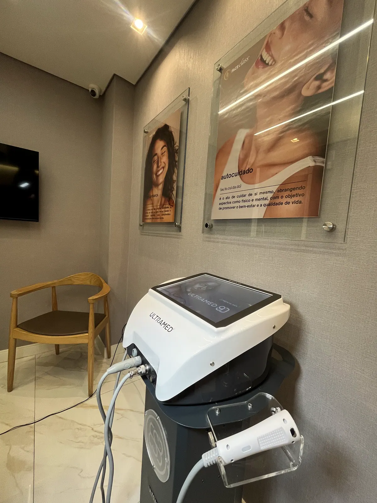 Equipamento de ultrassom microfocado na sala de procedimentos, com quadros de pele na parede